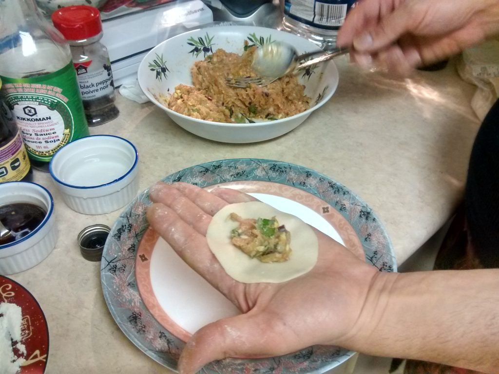 dumpling wrapper in open hand with meat inside