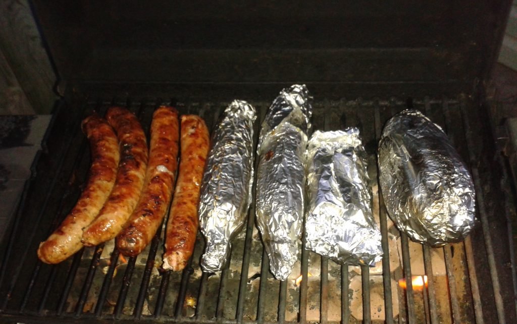 Sausages and baked potatoes on the BBQ