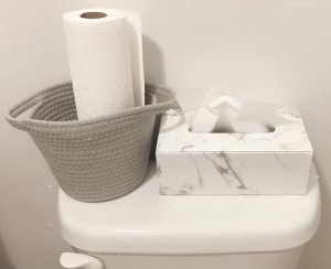 Marble tissue holder on the toilet next to a paper towel basket