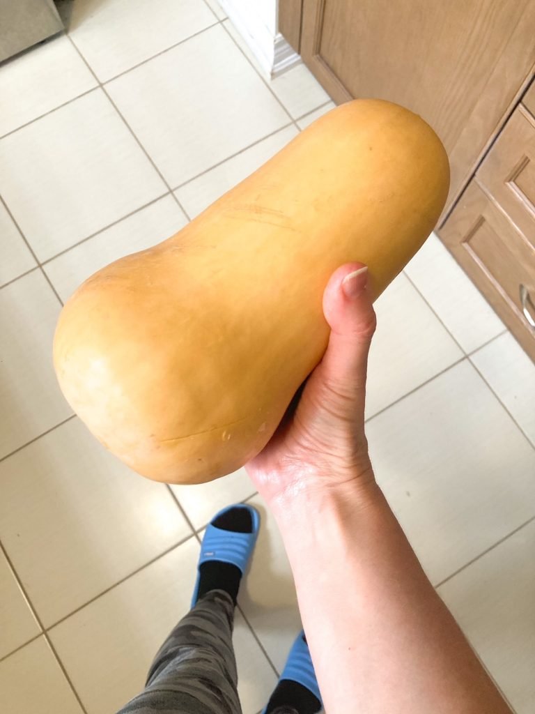 hand holding a butternut squash in the kitchen